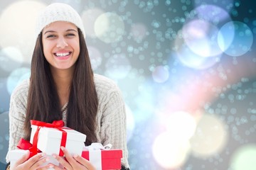 Composite image of festive brunette holding gifts