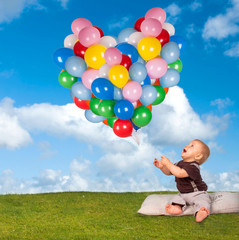 kleiner Junge mit Ballons auf der Wiese