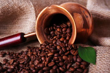 Coffee beans in ibrik on sacking background closeup