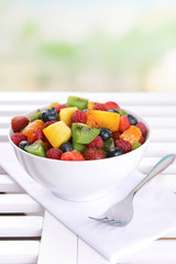 Delicious fruits salad in plate on table on light background
