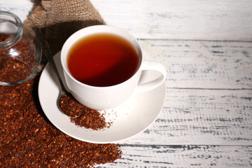 Cup of tasty rooibos tea, on old white wooden table