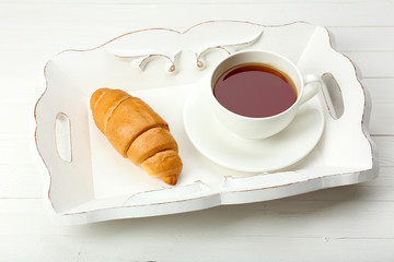 Delicious breakfast with cup of tea, fresh croissant