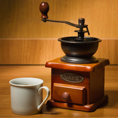 Old coffee grinder and cup on a table