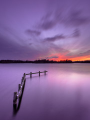 Purple Sunset over Tranquil Lake with Wooden Mooring Post