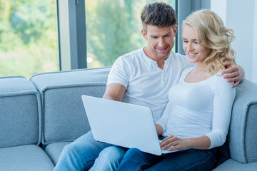 Young couple sitting sharing a laptop computer
