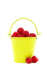 Raspberries in a bucket on a white background.
