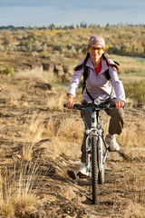 Fototapeta na wymiar Adult woman pedaling on a mountain bike on off-road