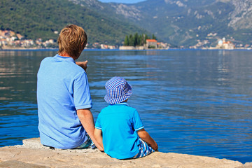 father and son looking at scenic view on sea vacation