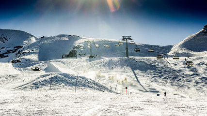 Beautiful snowy landscape with machines for skiing slope prepara