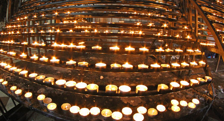 candlestick in church with many wax candles lit by faithful