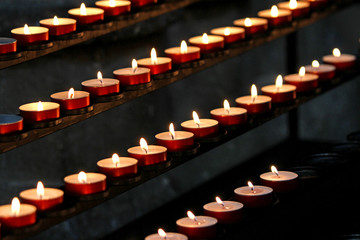many wax candles lit in the Church during mass - obrazy, fototapety, plakaty