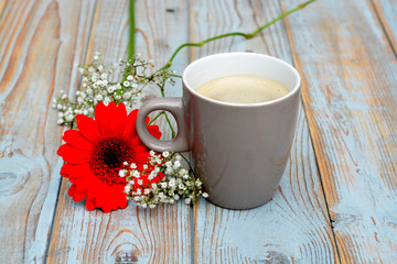 Koffiekop met rode gerbera op oud hout