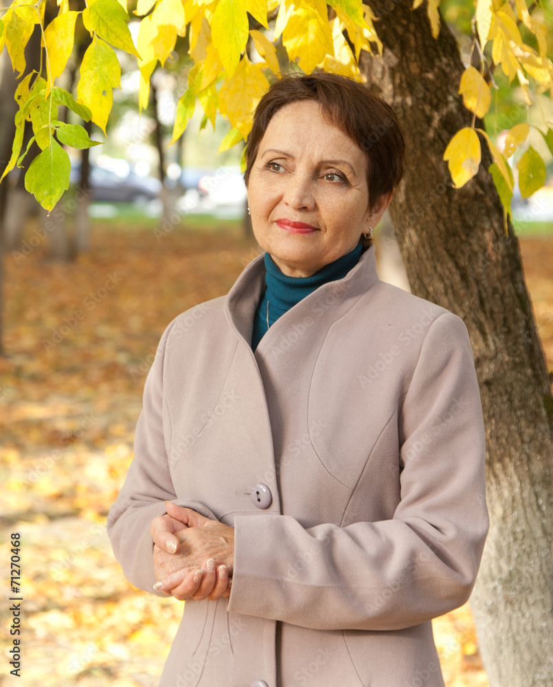 Wall mural attractive woman 50 years in the autumn park