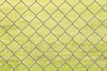 Naklejka premium Metal mesh fence and green grass at background