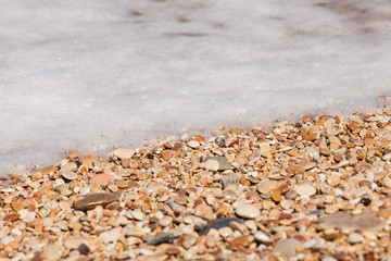 primo piano di un'onda che si infrange sulla riva piena di sassi