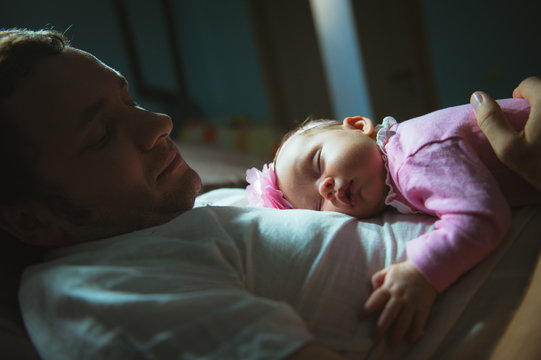 Image of young dad with cute little daughter in his arms