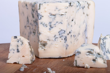 Blue cheese with slices on wooden board. Shallow depth of field