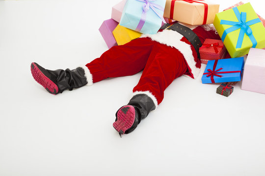 santa claus too tired to lie on floor with many gift boxes