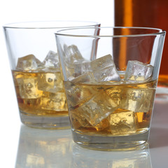 Whisky oder Whiskey im Glas und Flasche mit Eiswürfel