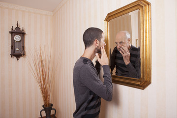 young man looking at an older himself in the mirror