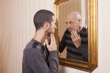 young man looking at an older himself in the mirror - obrazy, fototapety, plakaty