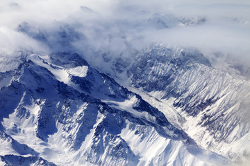 Obraz premium Top view on snow mountains and glacier in mist