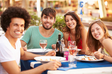 Group Of Young Friends Enjoying Meal In Outdoor Restaurant