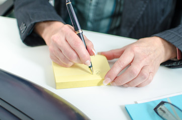 Businesswoman taking notes on a post it