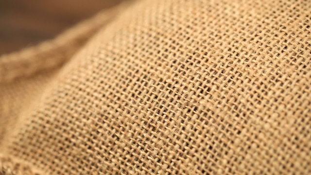 jute sack with coffee beans on wooden table (dolly shot)