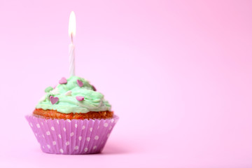 Delicious birthday cupcake on table on pink background
