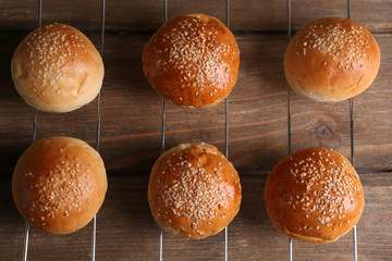 Tasty buns with sesame on oven-tray, on wooden background