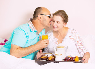 Obraz na płótnie Canvas Middle aged couple having breakfast in bed of a house hotel 