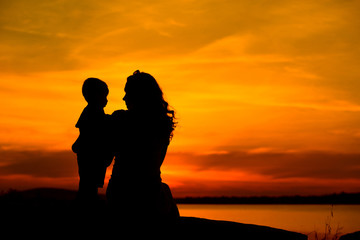 Fototapeta na wymiar Silhouette of a young mother with her little child
