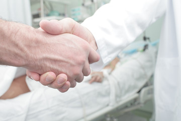 Fototapeta premium Handshake patient and doctor in hospital ward