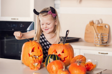 Kid on Halloween party making carved pumpkin