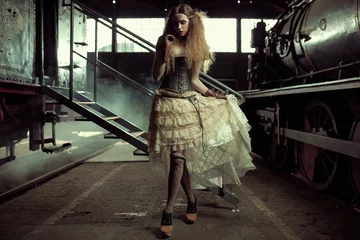 Rolgordijnen Artist KB Jonge geklede vrouw in het lege treinstation