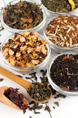 assortment of dry tea in glass bowls on wooden surface