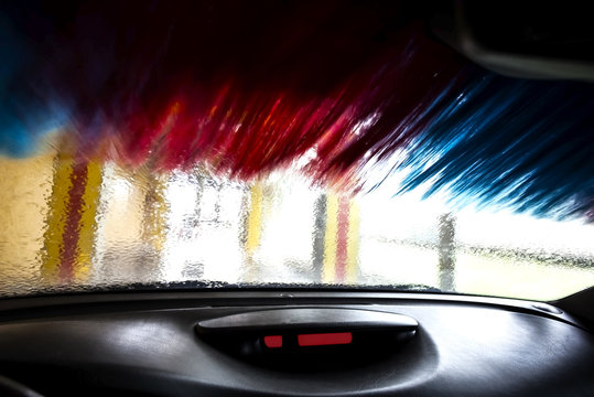 Car from inside a during the wash with rotating brushes, conveyor car wash.