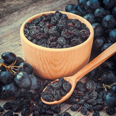 raisins in bowl and blue grapes on table