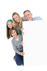 Cute family smiling at camera holding poster