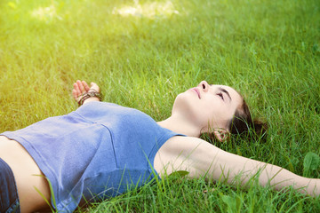 teenage girl laying on a meadow with stretched out arms
