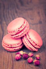 Macaroons with dry roses on retro vintage wooden background
