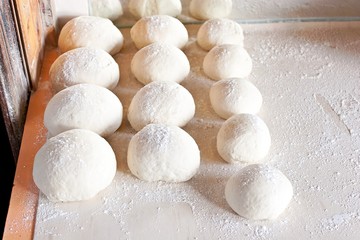 Rows of pizza dough on table