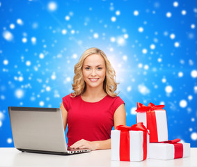 smiling woman in red shirt with gifts and laptop