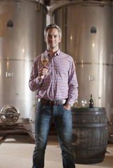 Professional winemaker, looking at camera, in his cellar with mo