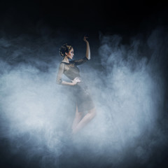 Young woman in a fashion dress posing in the fog
