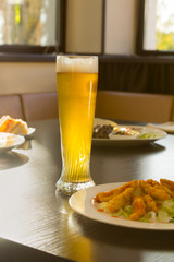 Tall Glass of Beer on Restaurant Table with Food