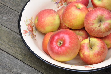 Fresh apples in metal bowl on wooden table