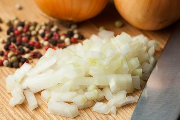 Chopped Onion on Wooden Cutting Board with Knife and Pepper