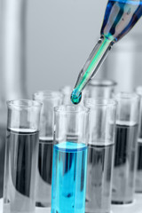 Laboratory pipette with drop of color liquid over glass test